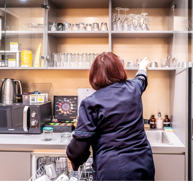 Agent de ménage Adapt propreté qui range un lave vaisselle.