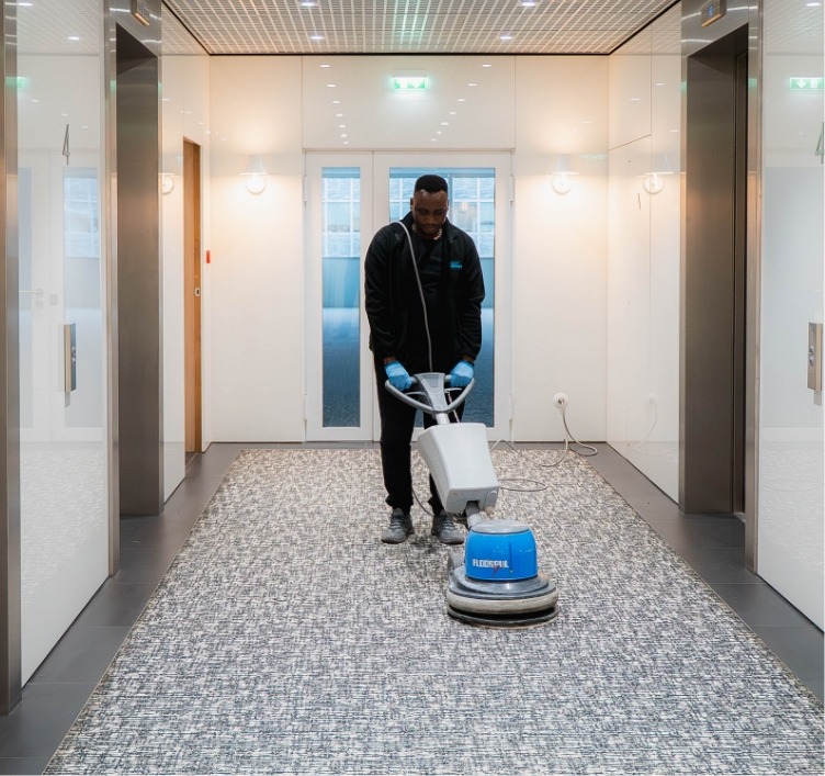 Agent de nettoyage Adapt Propreté utilisant du matériel spécifique pour nettoyer le sol.